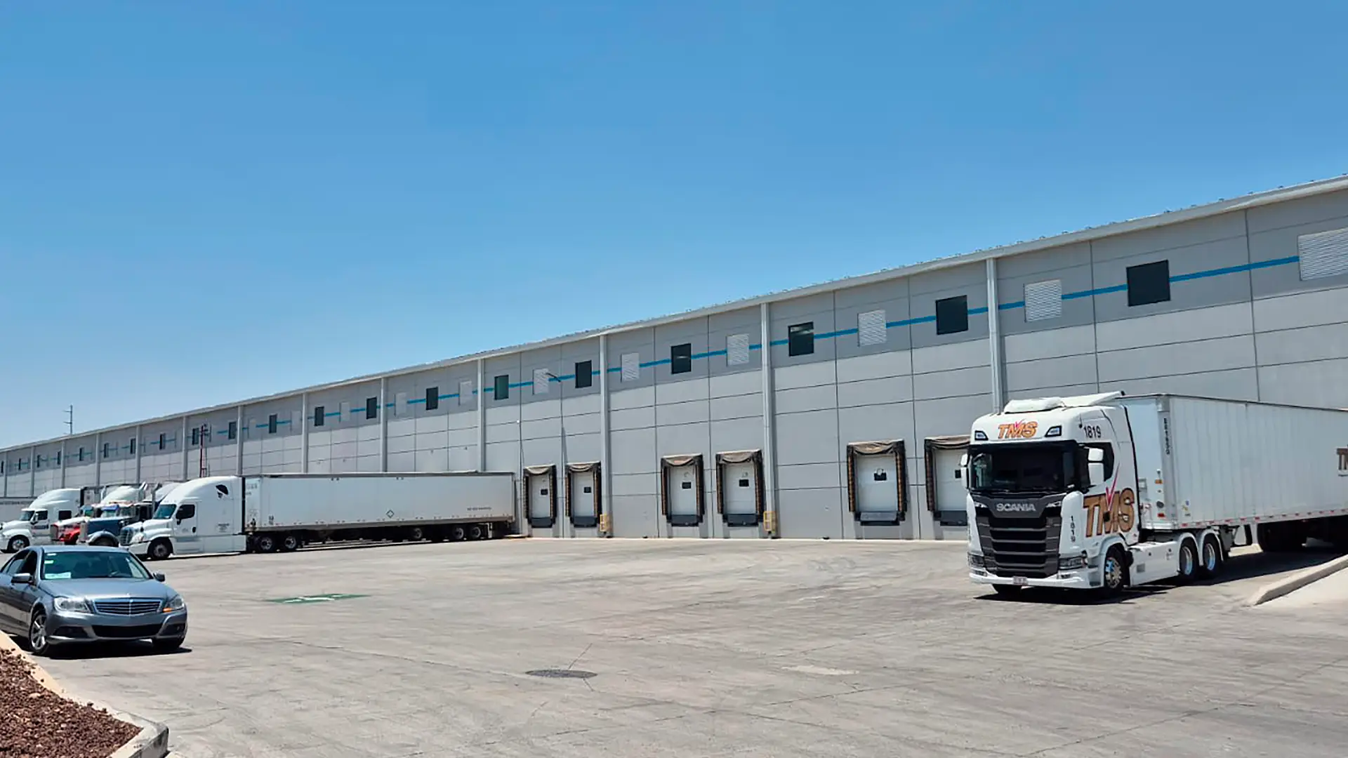 Exterior de bodega industrial con 8 andenes de carga, área de maniobras y estacionamiento para trailers